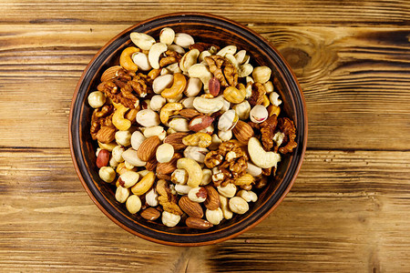 木桌上的混合坚果核桃开心果杏仁花生腰果榛子放在陶瓷碗里健康饮食图片