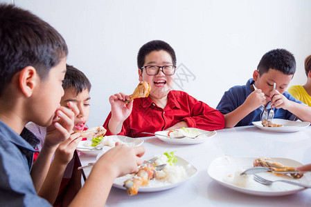 在学校食堂与朋友共进午餐时微笑的年轻图片