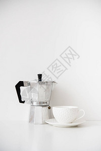 金属制咖啡机和白瓷杯桌上面有空白墙图片