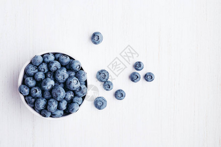 白色木桌上碗里的成熟蓝莓顶视图图片