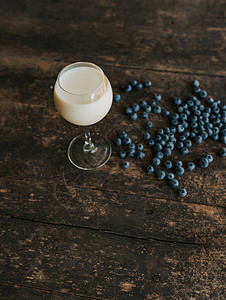 一个透明的玻璃杯加牛奶蓝色新鲜蓝莓散落在一张破旧图片