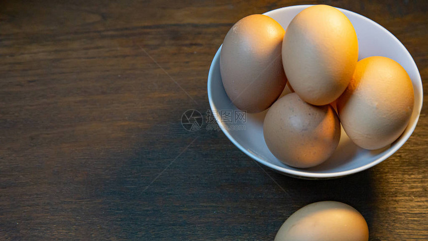 鸡蛋在木质桌上的碗里以图片