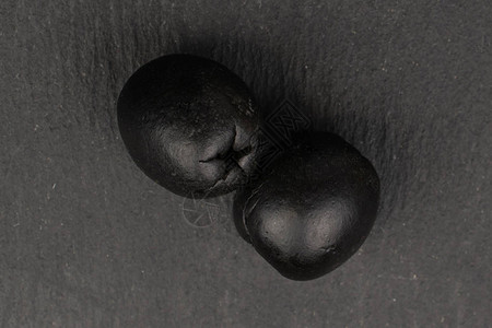 灰色石头上的两个全美味黑橄榄平板图片