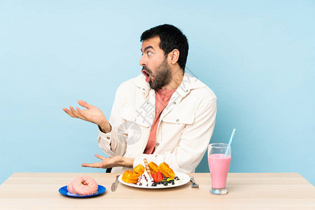 男人在餐桌上吃早餐华夫饼和奶昔面部图片