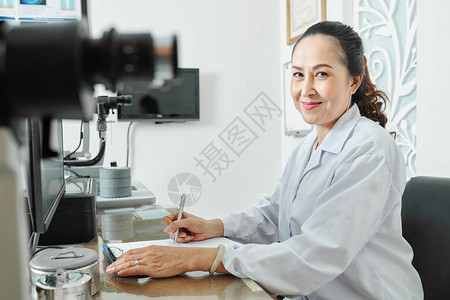 亚洲女验光师在医院使用医疗设备时坐在桌边看图片
