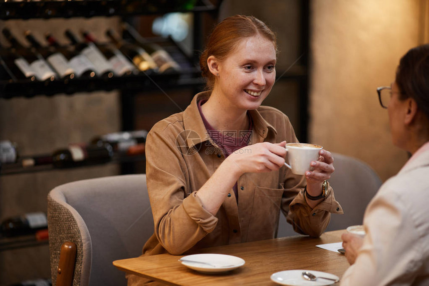 微笑的年轻女子在咖啡馆与朋友见面时图片