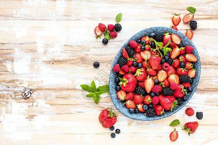 木桌上鲜熟的草莓蓝莓和黑莓上图片