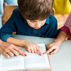 妇女和儿童在近男孩的书上用手指图片