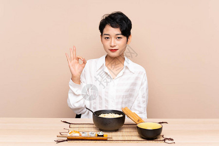 坐在桌边的亚洲女孩面碗和寿司手指图片