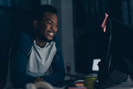 在看电脑监视器时笑着的非洲美国人程序员图片