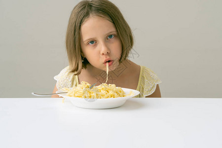 在白桌上吃意大利面的小女孩图片