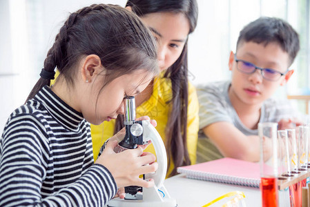 年轻女学生在科学课堂上看显微镜背景图片