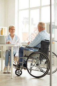 女医生为轮椅上高级男子提供咨询的全长女医生肖图片