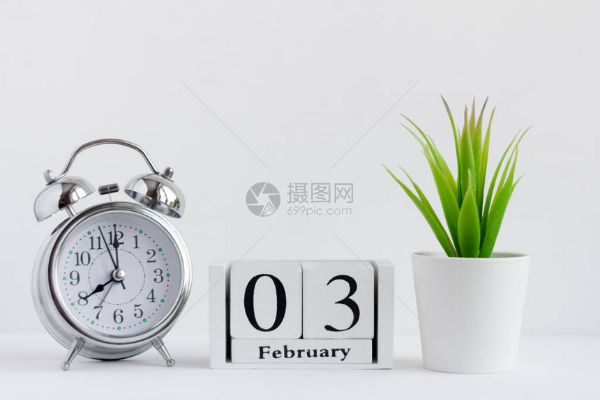 2月3日在白色背景的木制日历上闹钟和日历图片