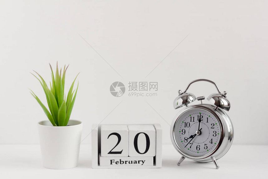 月20日在浅色背景的闹钟旁边的木制日历上一年中的一天概念世图片