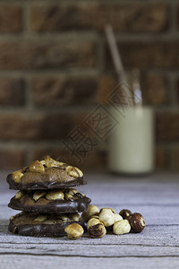 堆叠的榛子和巧克力饼干牛奶瓶和榛子放在砖背景的木桌上图片