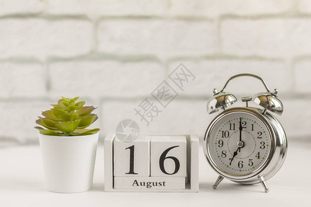 月16日在闹钟旁边的木制日历上夏季的一天图片