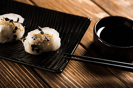 近在筷子和木制桌上酱油边的盘子上紧贴地看着美味的图片