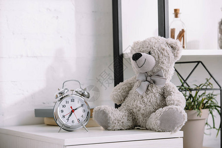 床头柜上的闹钟和灰色泰迪熊图片
