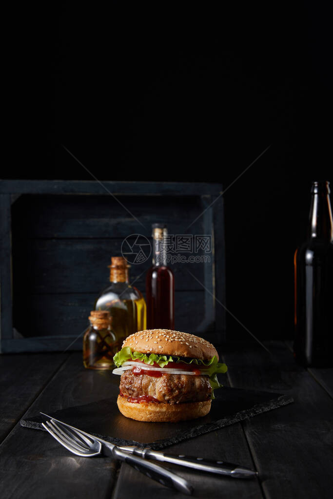 汉堡有选择焦点在黑切板上靠近餐具油醋和图片