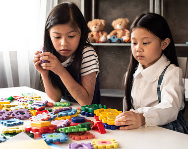 两个小女孩在家庭工作室一起玩塑胶游戏带着有兴趣的感觉露丝闪光效应周背景图片