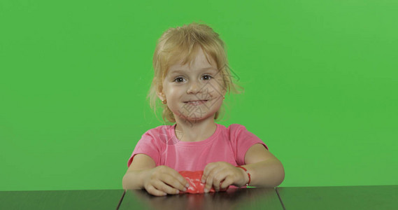 快乐的小女孩在色度键背景上玩橡皮泥图片