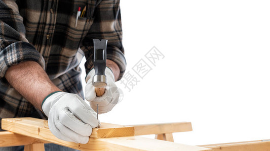 特写木匠用他的双手用锤子和钉子的手套保护着一块木板建造图片