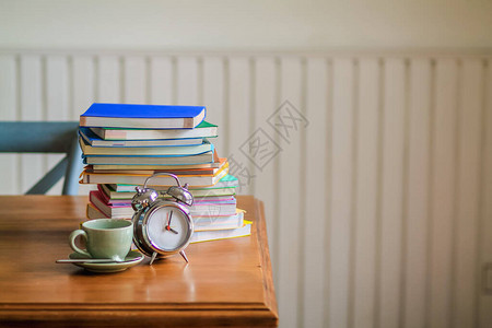 屋内的一个木制桌子上放着多彩的书籍和闹钟图片