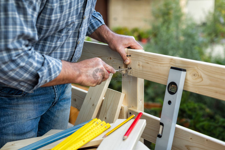 成年木匠工用螺丝刀拧螺丝以固定木栅栏的木板家务事自己图片