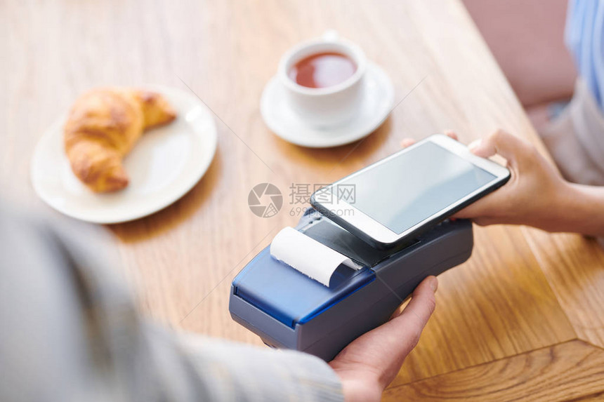 餐厅客人坐在桌边使用智能手机通过移动支付系图片