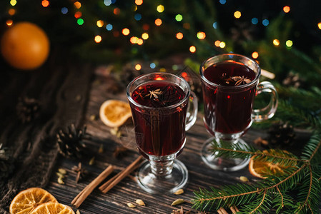 以圣诞树和圣诞节灯光装饰的木制桌子上配有果子杯面红葡萄酒图片