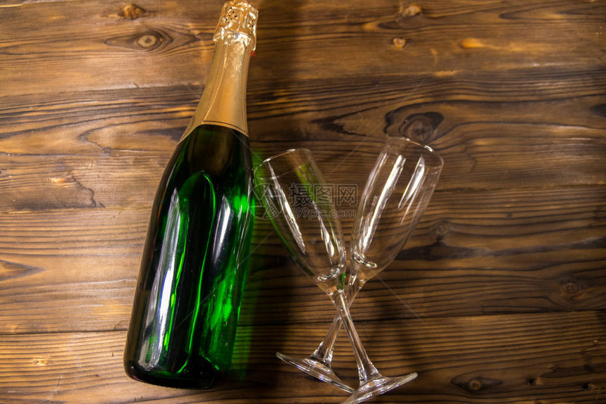 香槟酒瓶和两杯空香槟杯放在木制背景图片