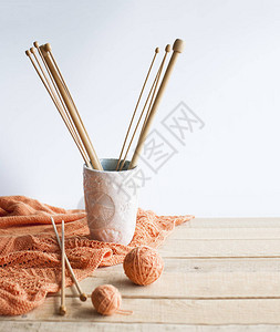 浅色木质背景上的木制织针线束橙色格子和手工制作的玻璃图片