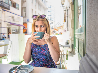 美丽的女人坐在街上咖啡厅喝咖啡或图片