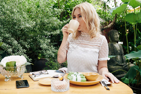 美貌优雅的年轻女子喝咖啡喝春卷在户外咖啡厅吃饭春图片