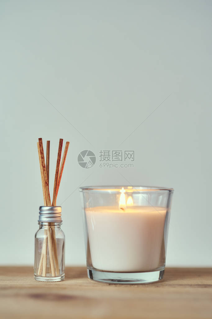 玻璃瓶中带有香棒的燃烧蜡烛图片
