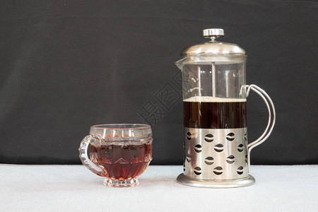 一个咖啡杯和桌上的法式压榨机图片