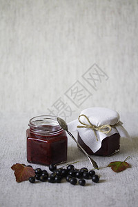 玻璃罐子里的黑花果酱新鲜果子和叶茎秋天收割和保护区有机食品图片