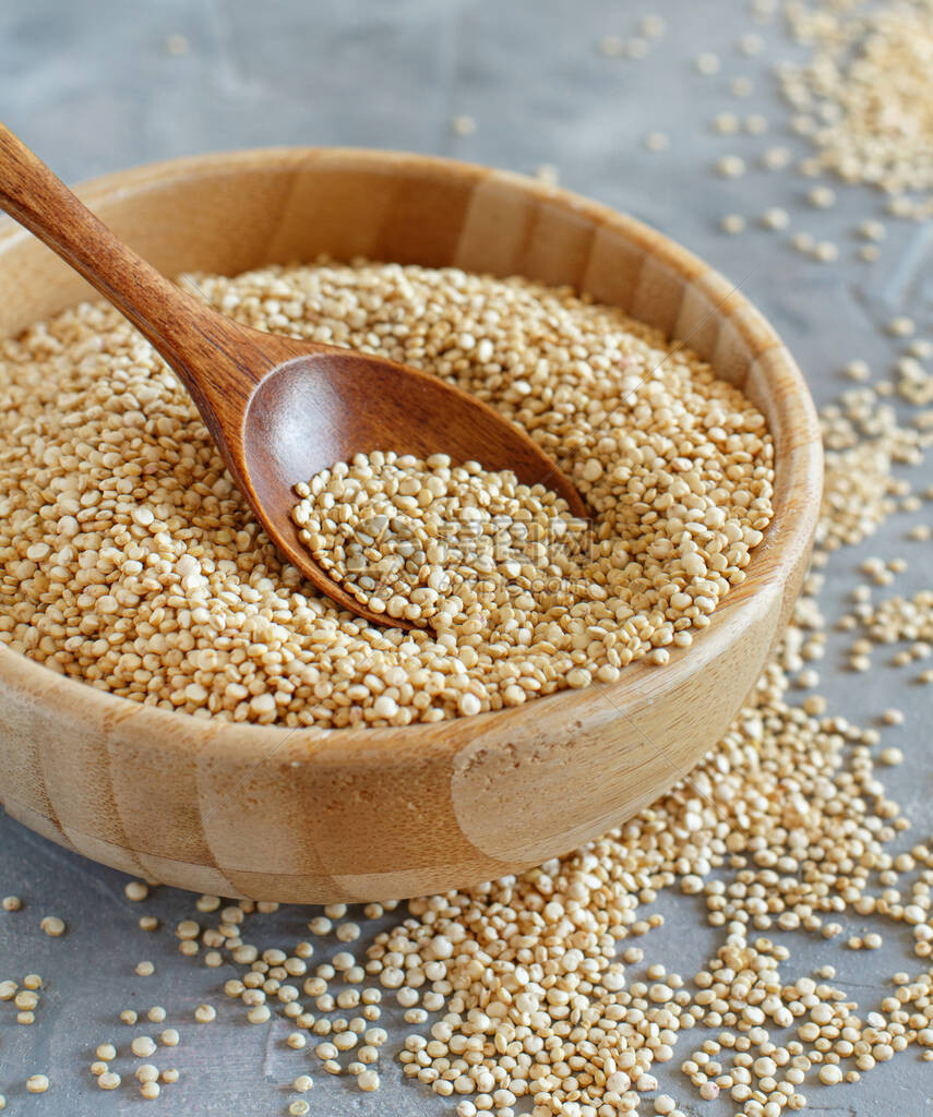 一碗生干白quinoa种子和勺子在灰图片