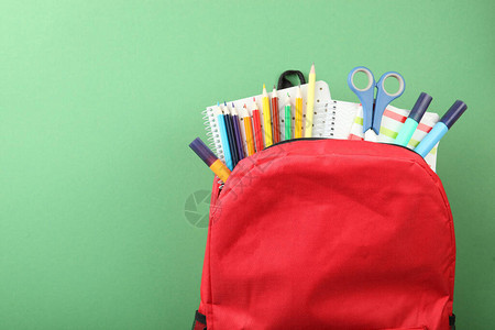 学校背包和学校文具在彩色背景的顶端视图上图片