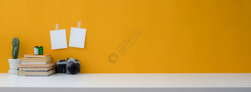以相机书籍仙人掌锅和黄色墙在白桌上复制空间的近视图片