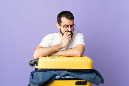 旅行的caucasian男子与一个手提箱装满衣物的手提箱在孤立的紫图片