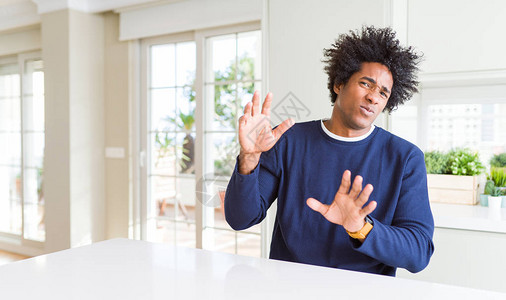年轻的非洲裔美国人穿着休闲毛衣坐在家里厌恶的表情图片