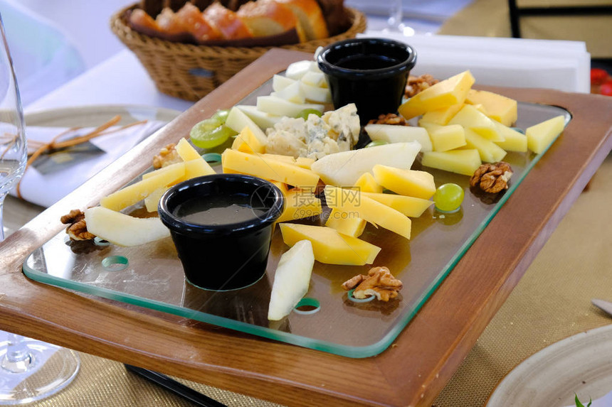在豪华餐厅的宴席桌上木质餐具上的几种切奶酪图片