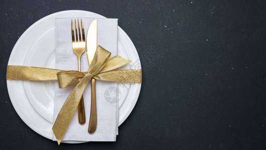 餐桌设置奢华正规白色盘子上的金餐具黑色图片