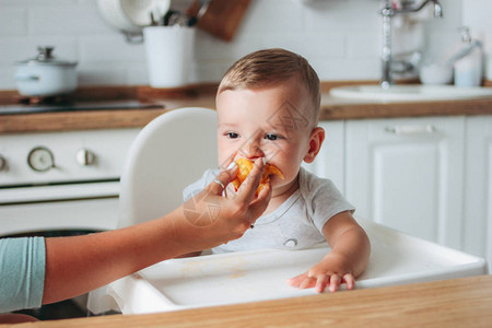 可爱的小男孩在厨房吃第一块食物桃子图片