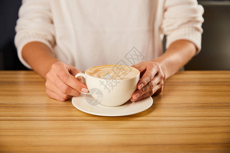 持有卡布奇诺咖啡杯的妇图片