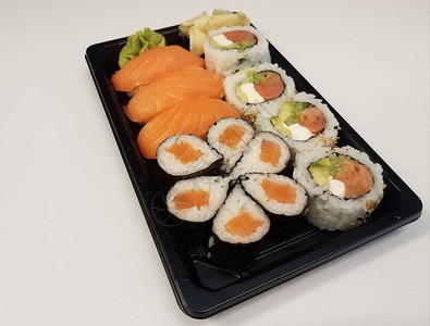 白色表面黑色塑料托盘中的橙色三文鱼寿司饭图片