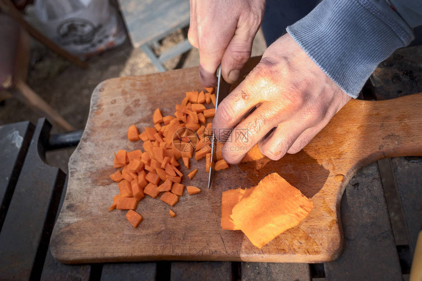特写男手用刀切胡萝卜做饭野餐图片