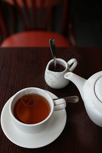 深色木质背景上的白色茶壶配红茶图片